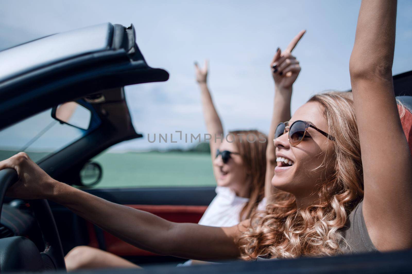 happy young women driving in in cabriolet car and laughing by asdf