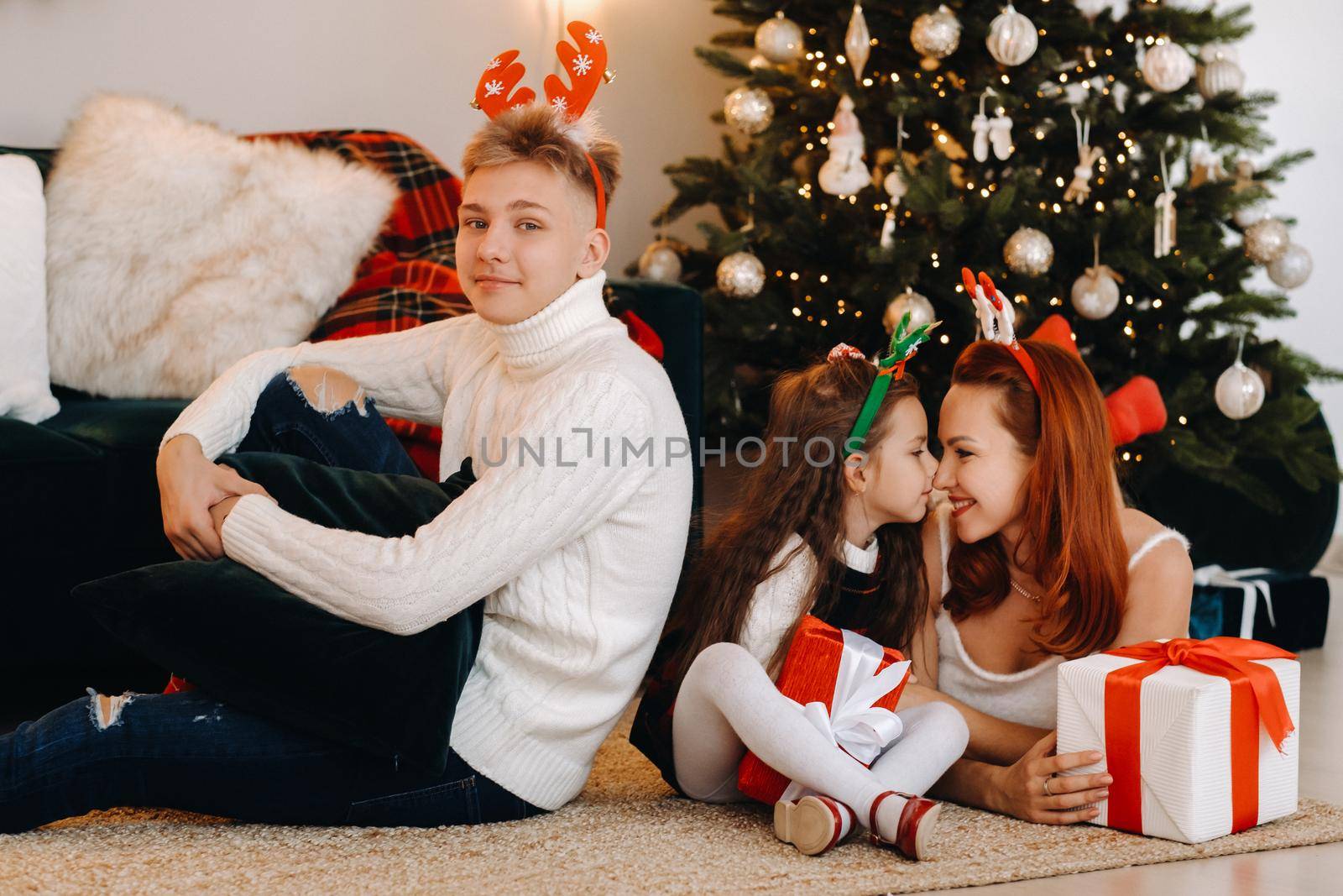 a happy family is lying on the floor of the house with New Year's gifts, next to the Christmas tree,