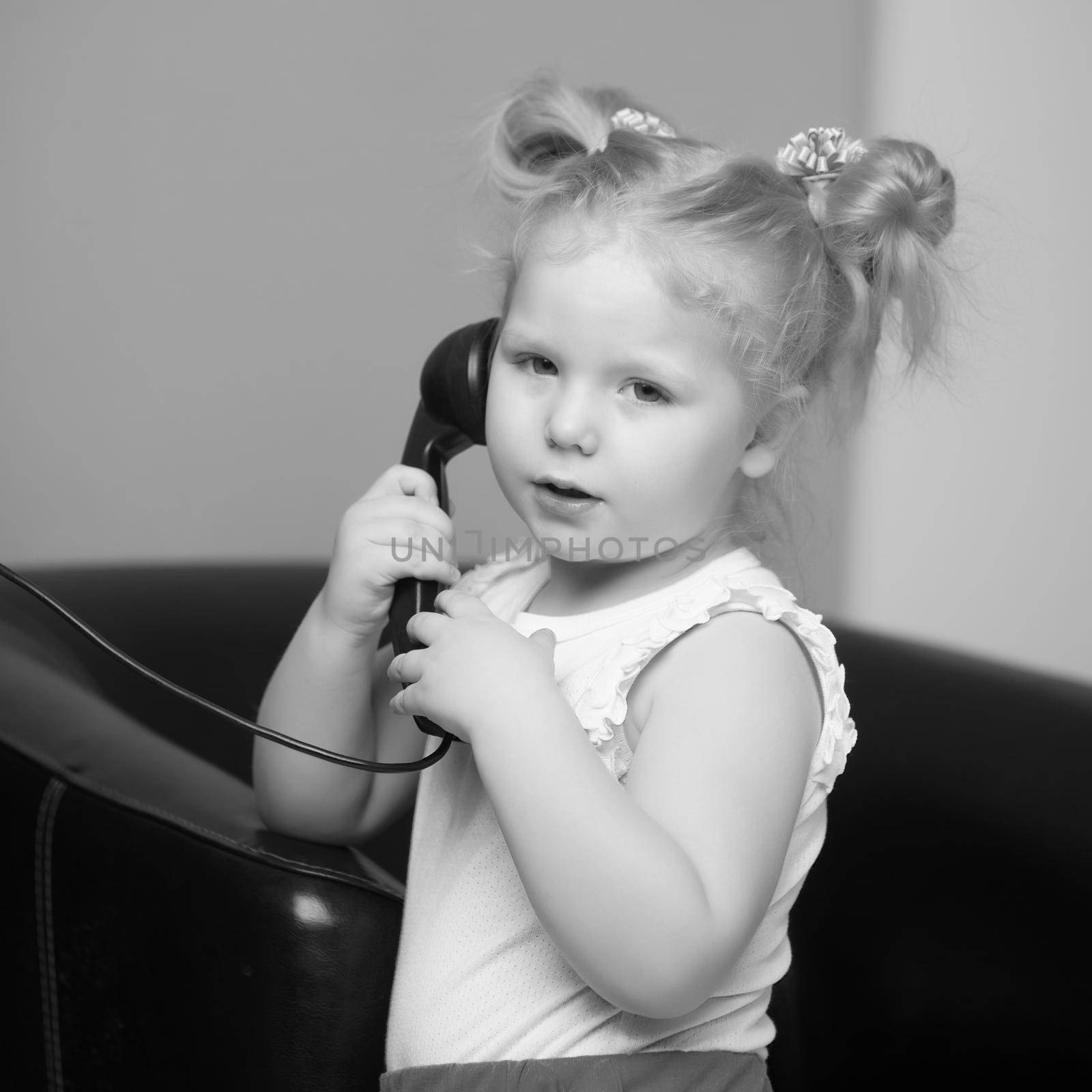 A little girl is ringing on the old phone. by kolesnikov_studio