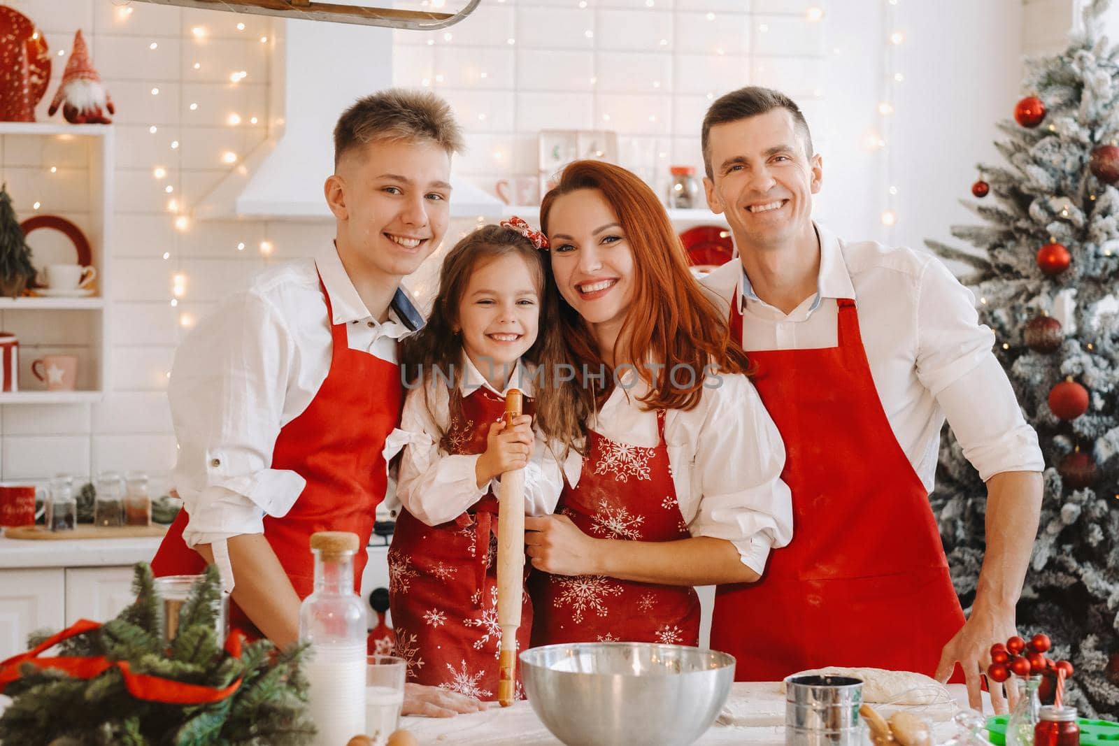 A happy family is standing in the Christmas kitchen and preparing dough for making cookies.