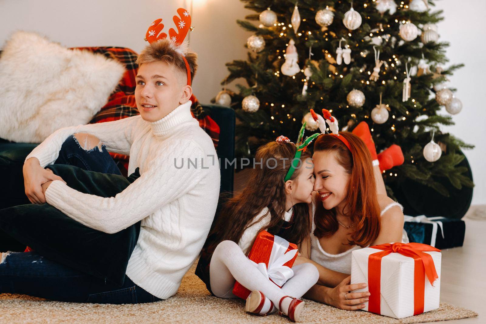 a happy family is lying on the floor of the house with New Year's gifts, next to the Christmas tree,