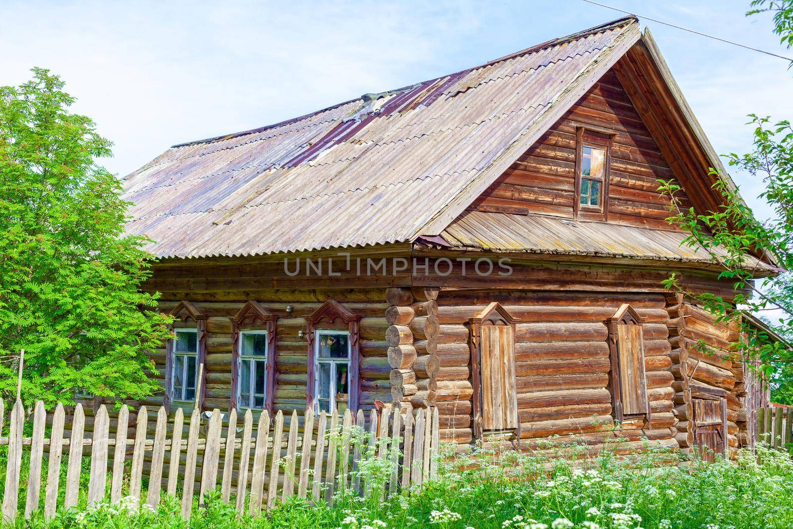 Old log house among dense trees in a village on the edge of Russia. A picturesque place for tourism.