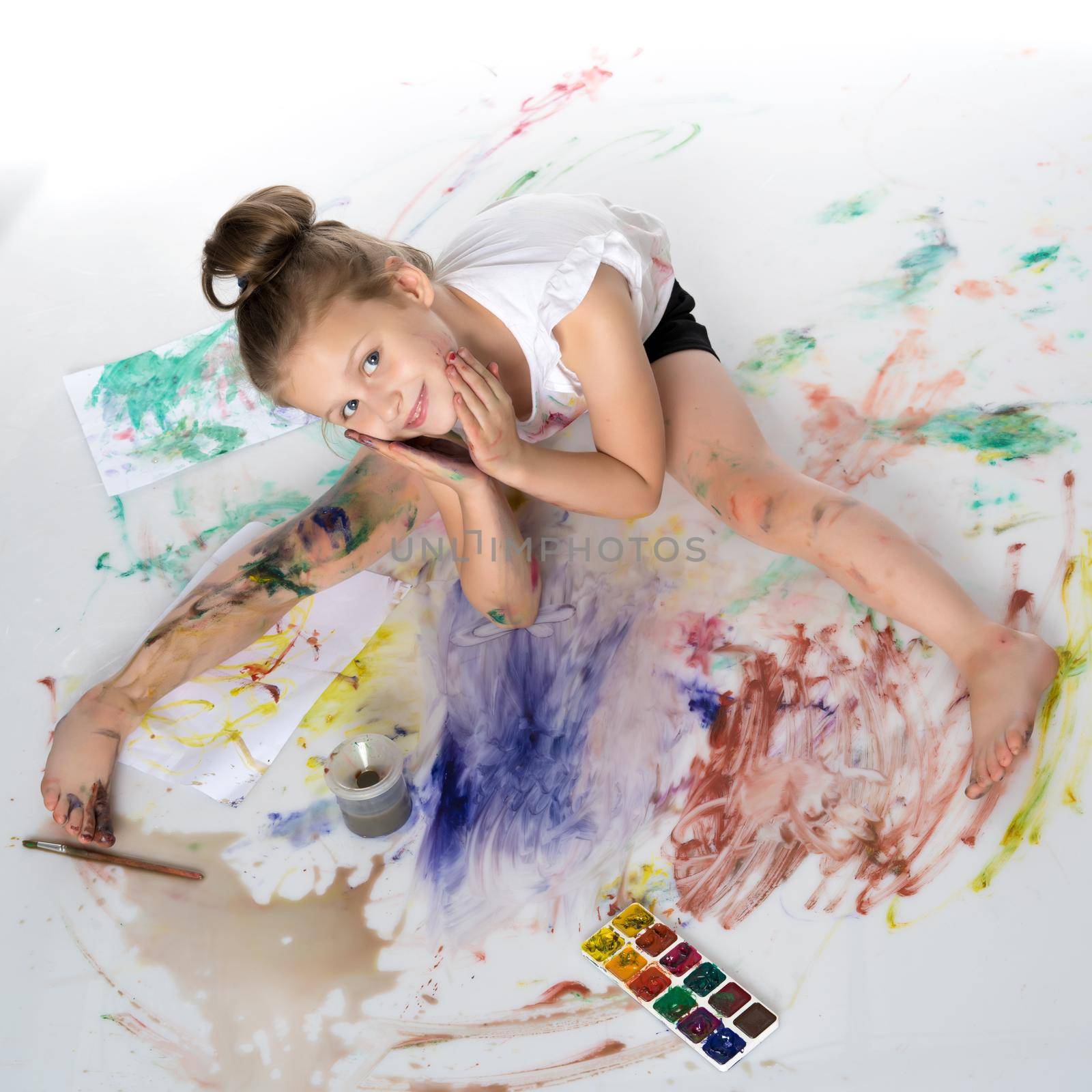 A little girl paints with paint and brush. The concept of children's creativity, happy childhood. Isolated on white background.