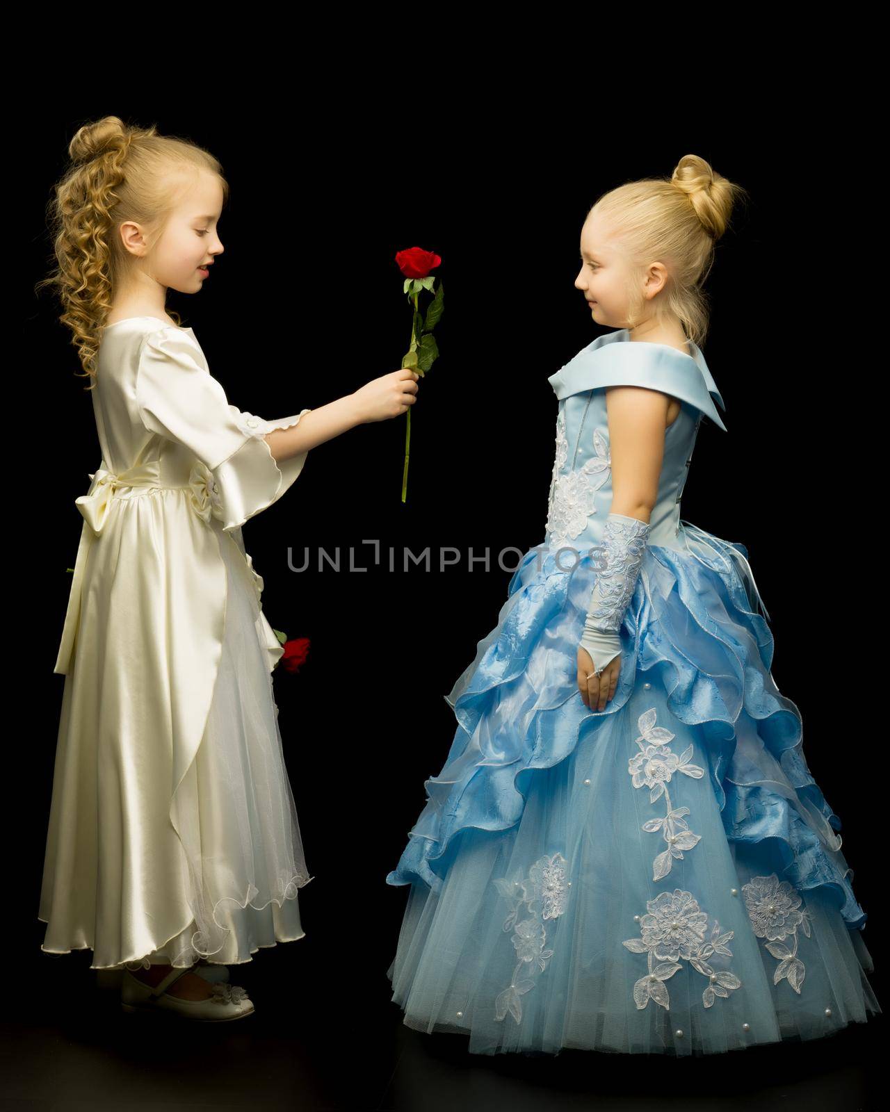 Two adorable princess girls with flowers on a black background. Concepts style and fashion.