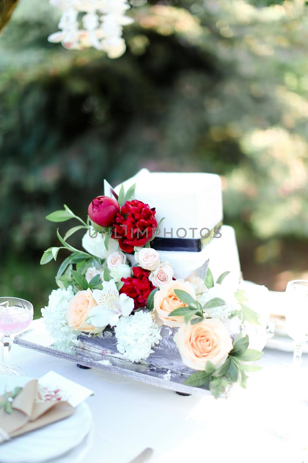 White wedding cake with red peony. Concept of bridal sweets.