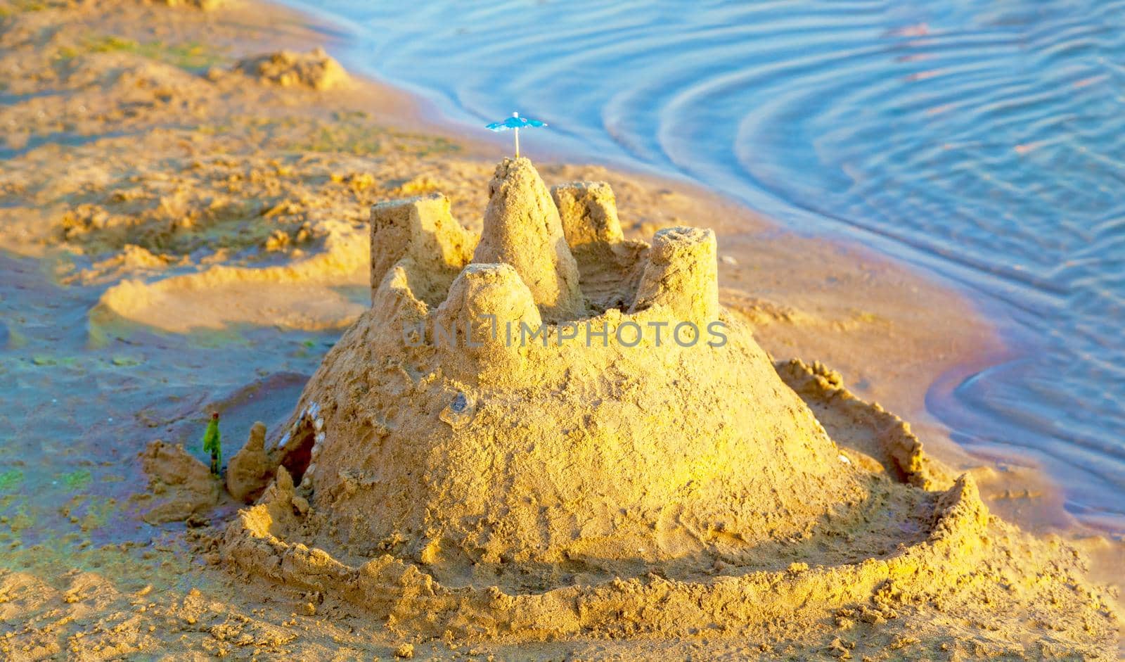 Beautiful sand castle illuminated by the morning sun on the beach of the tropical sea. The concept of a family vacation at sea.