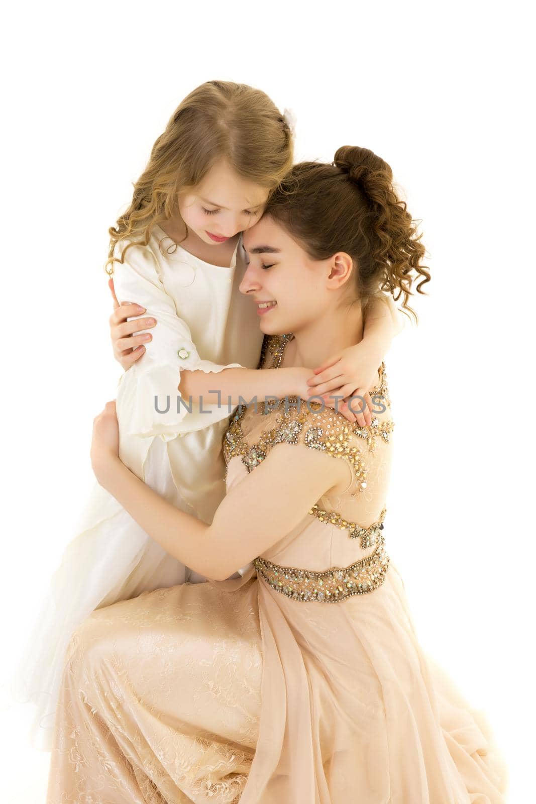 Beautiful young girl hugging her little sister. The concept of a happy childhood, family values. Isolated on white background.