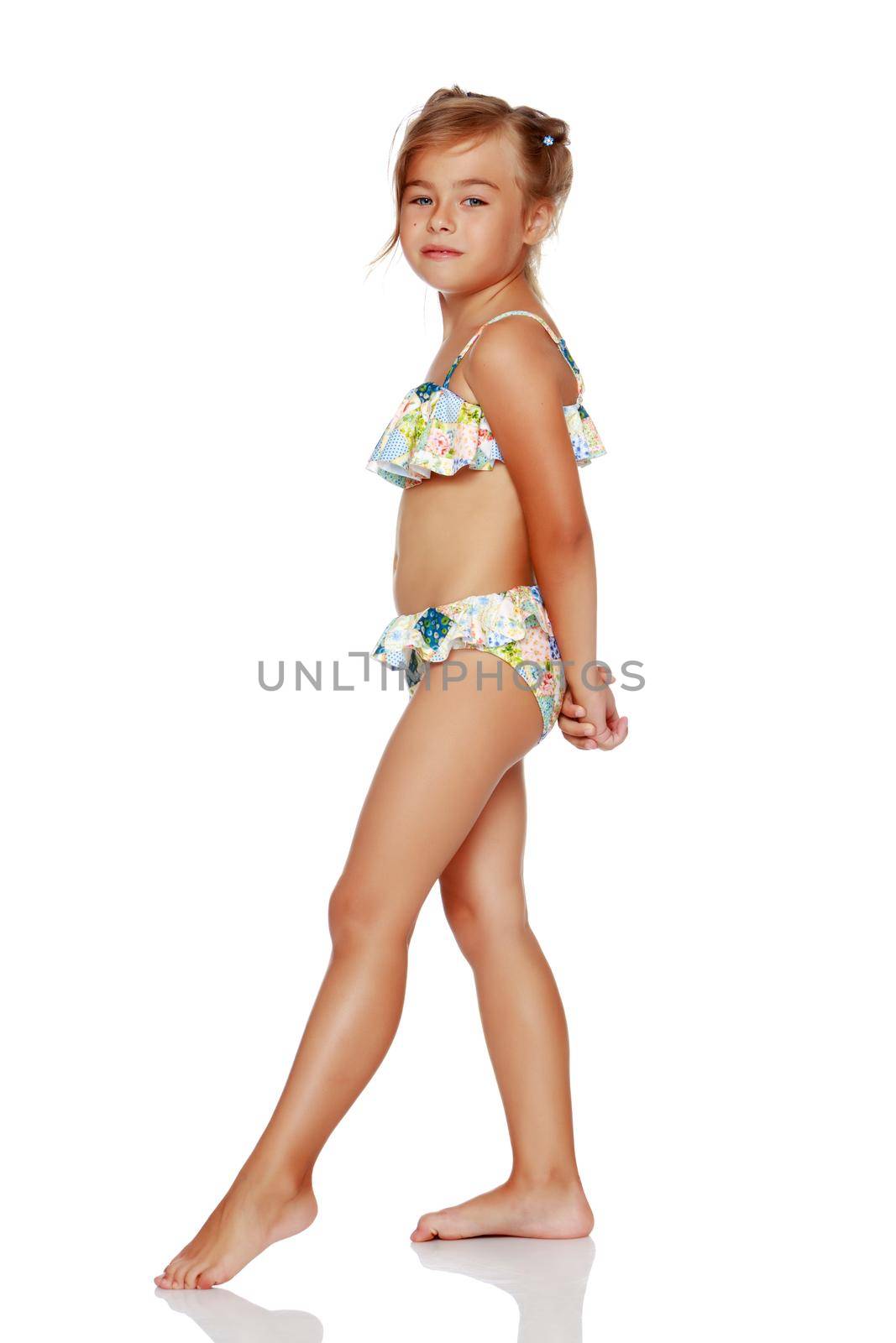 Tanned little girl in a swimsuit. The concept of summer family vacations in the sea. Happy childhood. Isolated on white background.