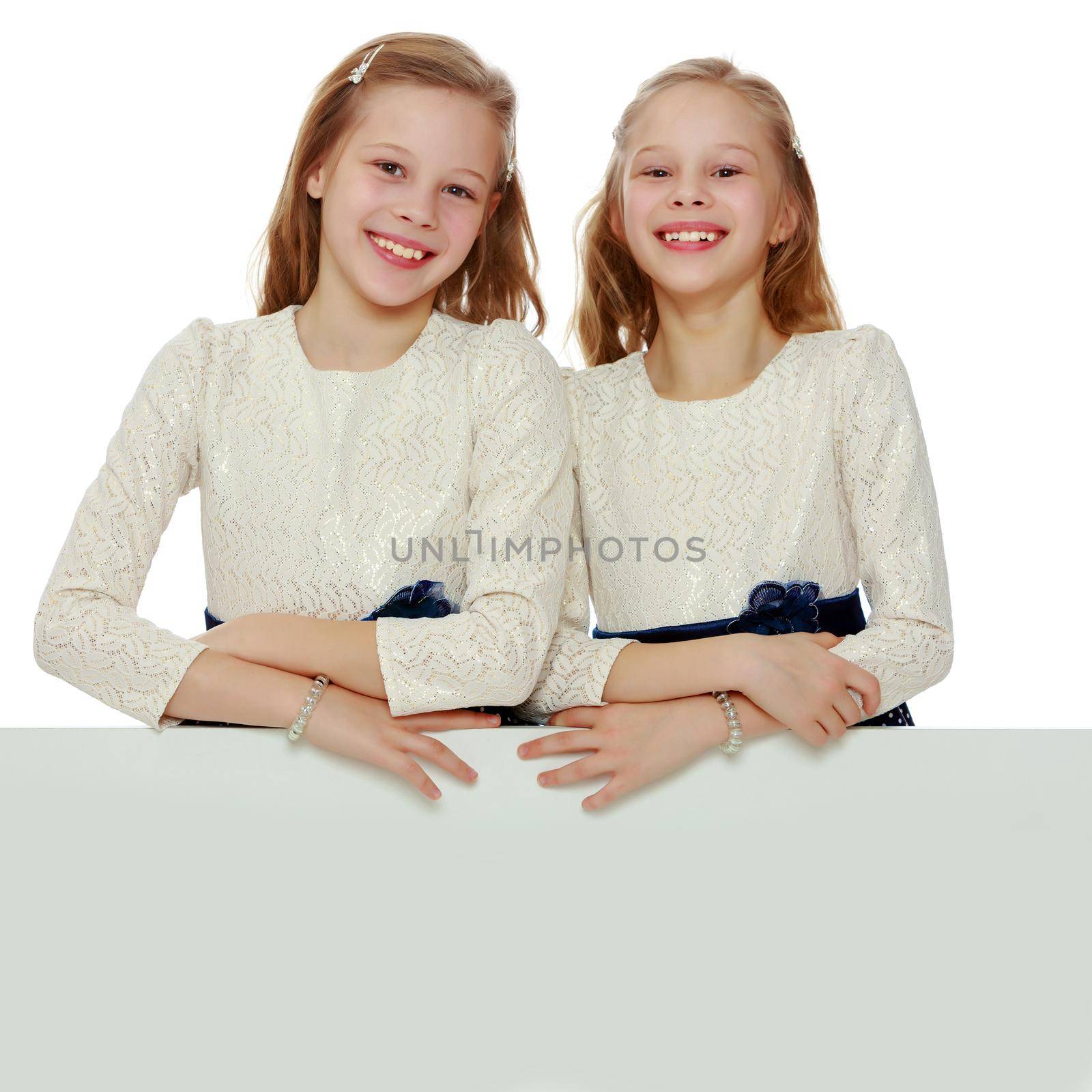 Two little girls peeking out from behind a white advertising ban by kolesnikov_studio