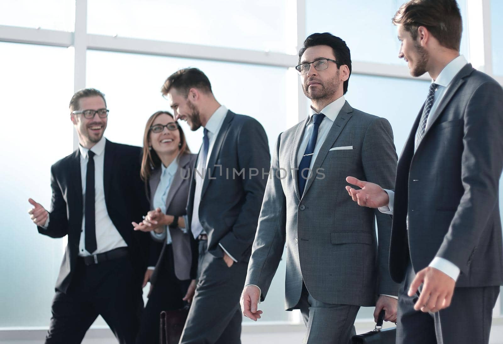 Confident businessman with colleagues strolling in the office