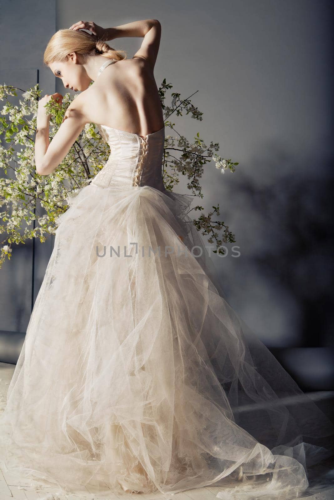 Bride in wedding dress behind bush with flowers by Julenochek