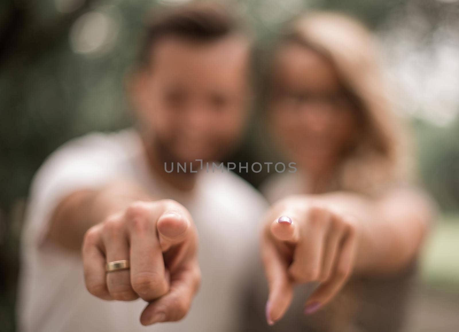 close up.happy married couple standing in the Park and pointing at you.