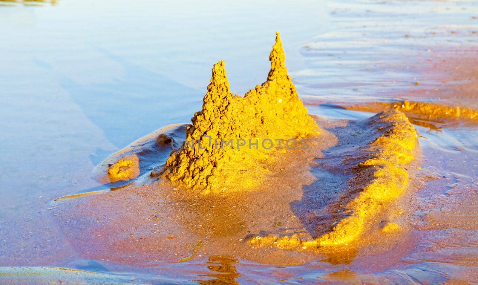 Beautiful sand castle illuminated by the morning sun on the beach of the tropical sea. The concept of a family vacation at sea.