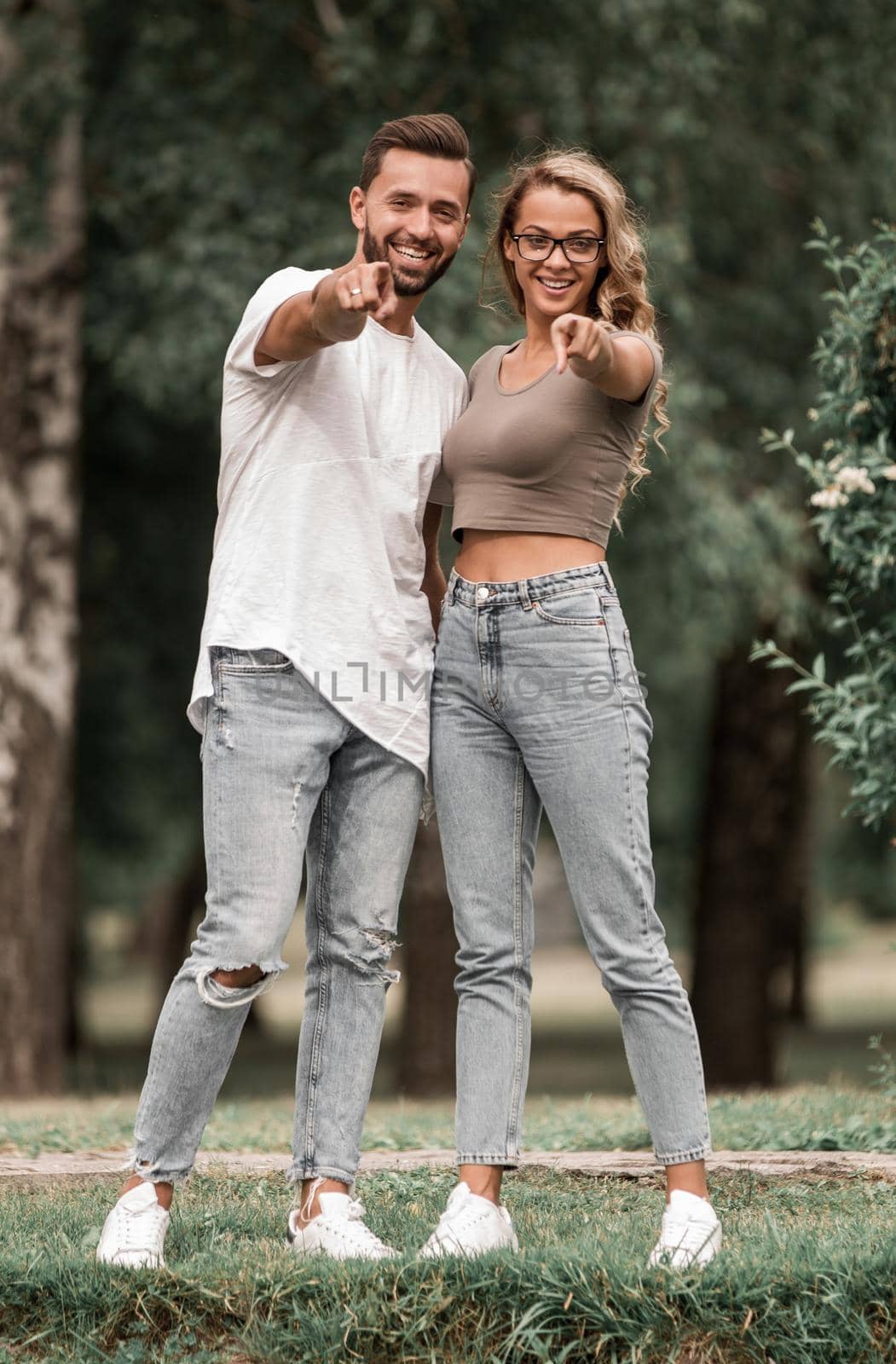 loving couple standing in the Park and pointing at you by asdf