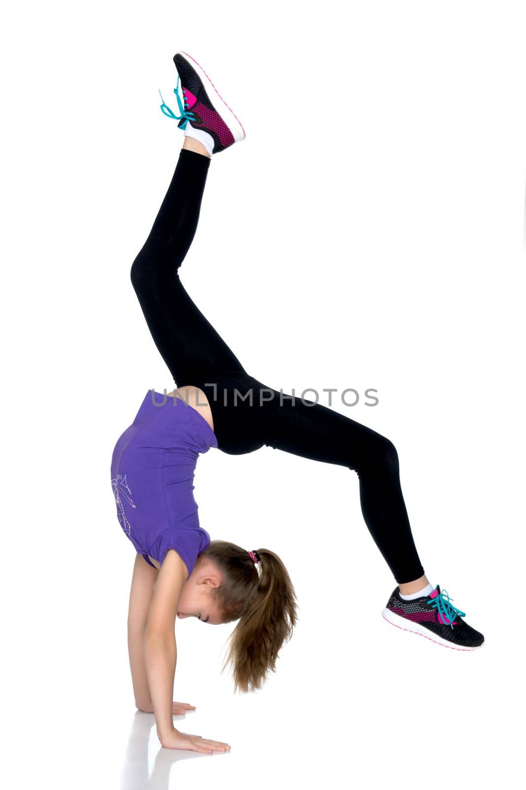 The girl gymnast performs a handstand with bent legs.The concept of childhood, sport, a healthy lifestyle. Isolated on white background.