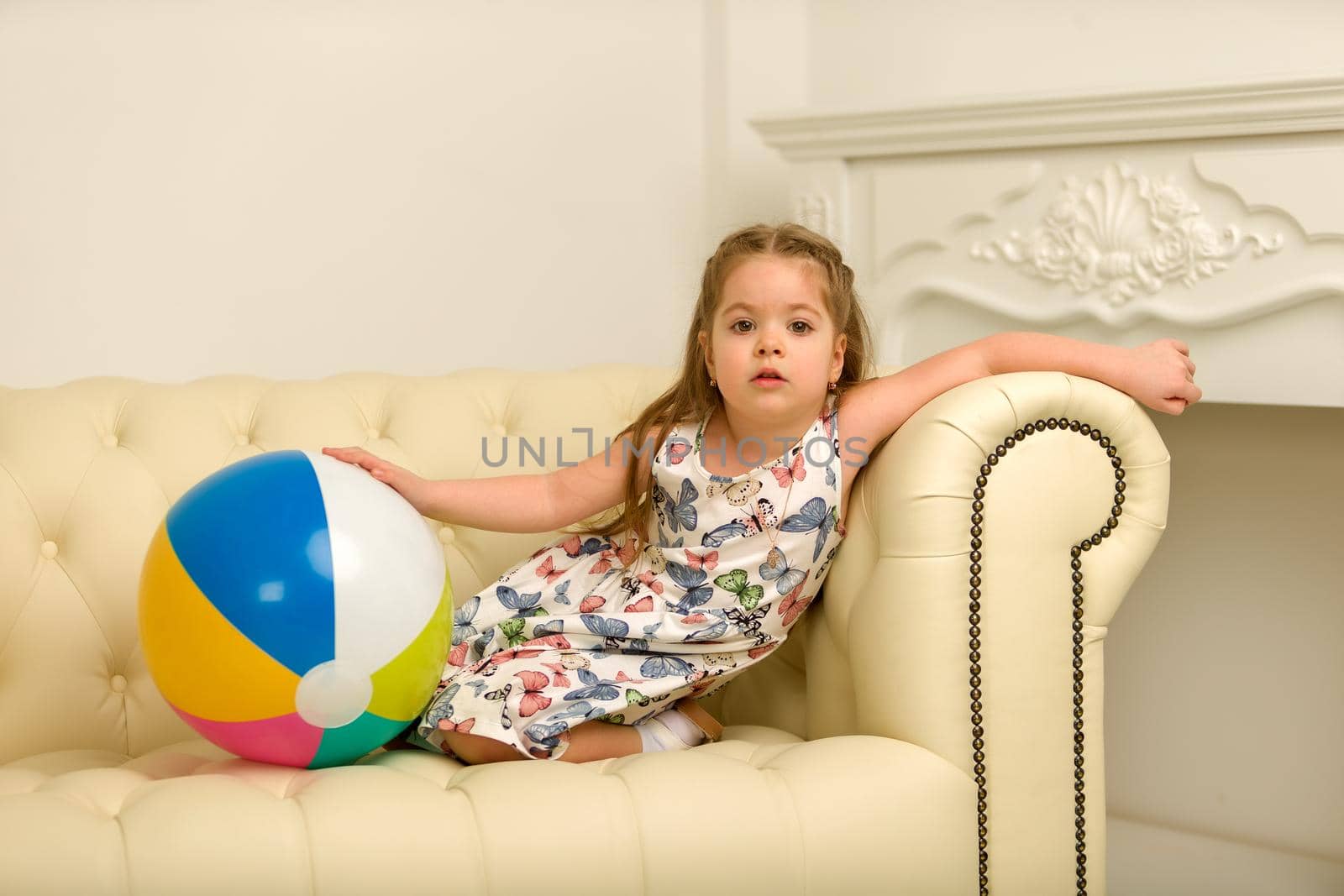 Little girl with a ball on the couch. by kolesnikov_studio
