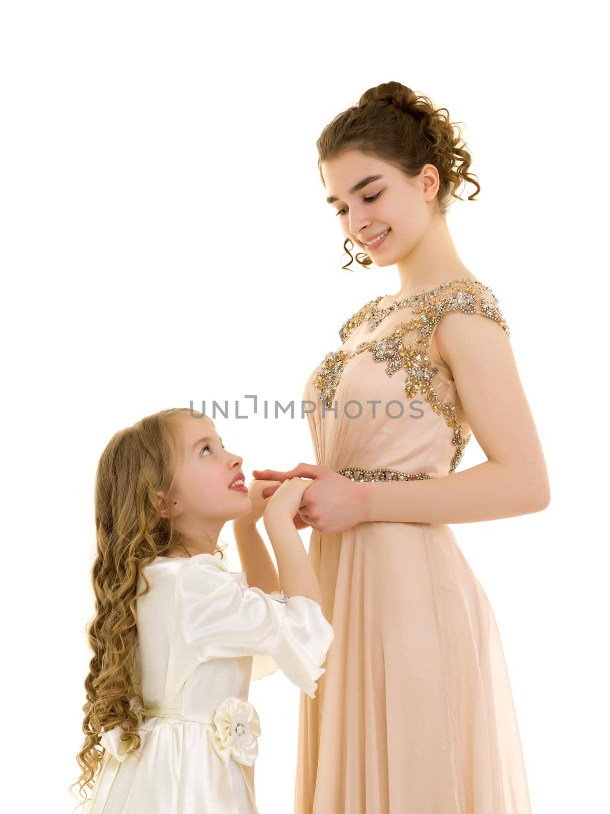 Beautiful young girl hugging her little sister. The concept of a happy childhood, family values. Isolated on white background.