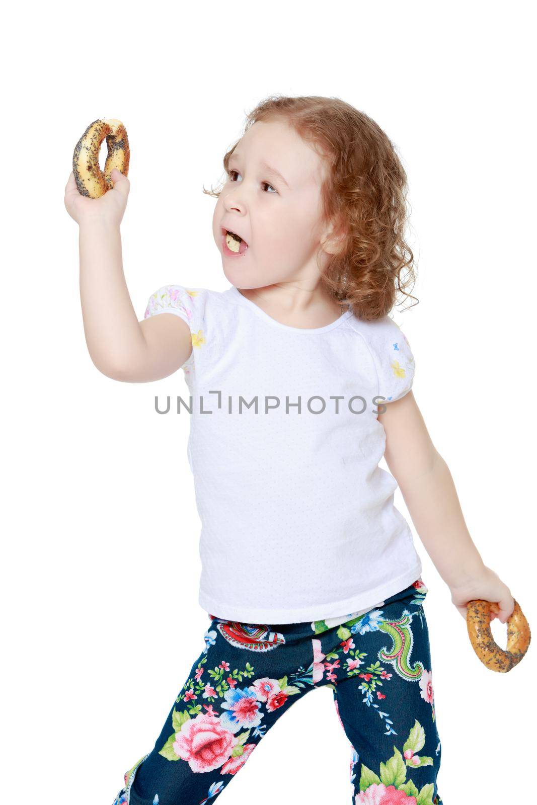 The little girl is eating a bagel. The concept of a healthy baby food. isolated on white background
