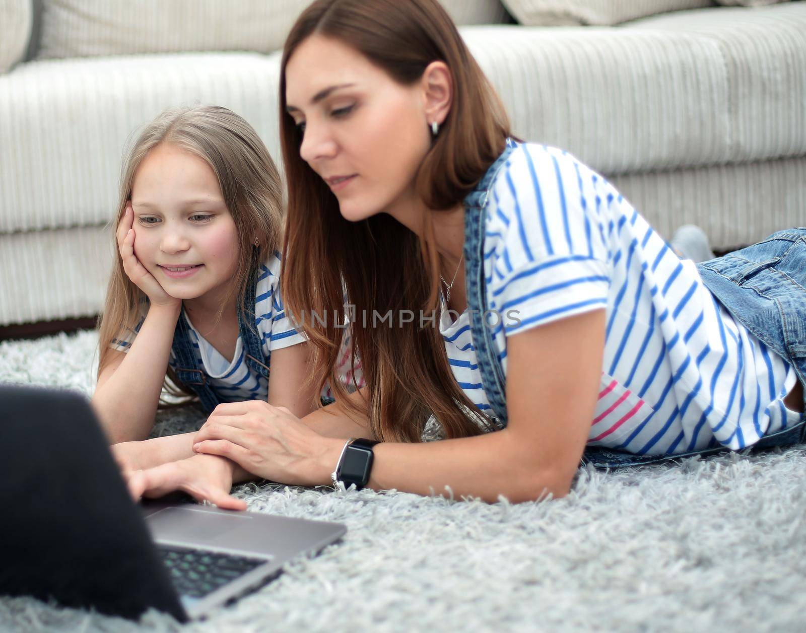 mother and daughter using a laptop in their home by asdf