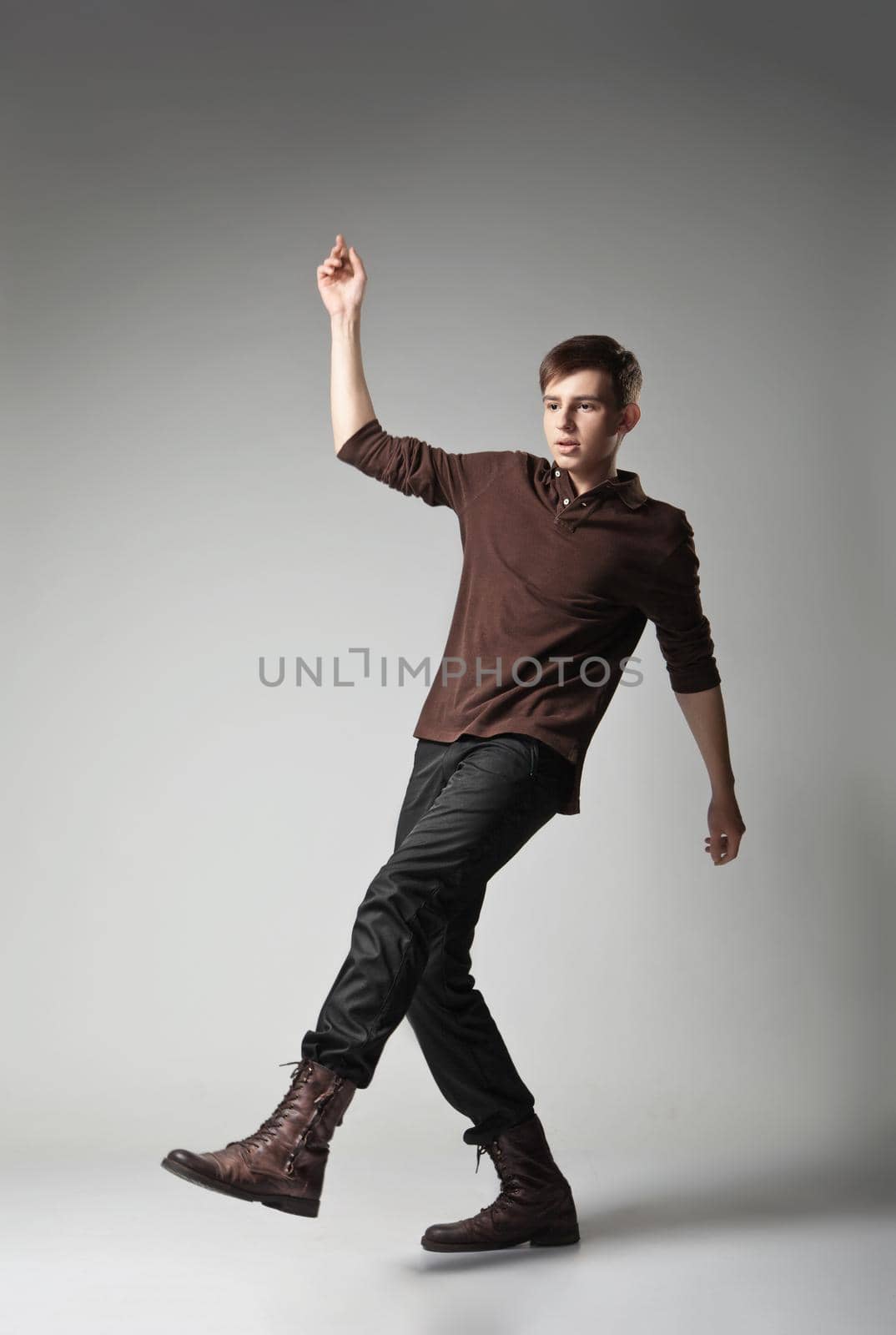Full length portrait of a young fashion male jumping on grey background
