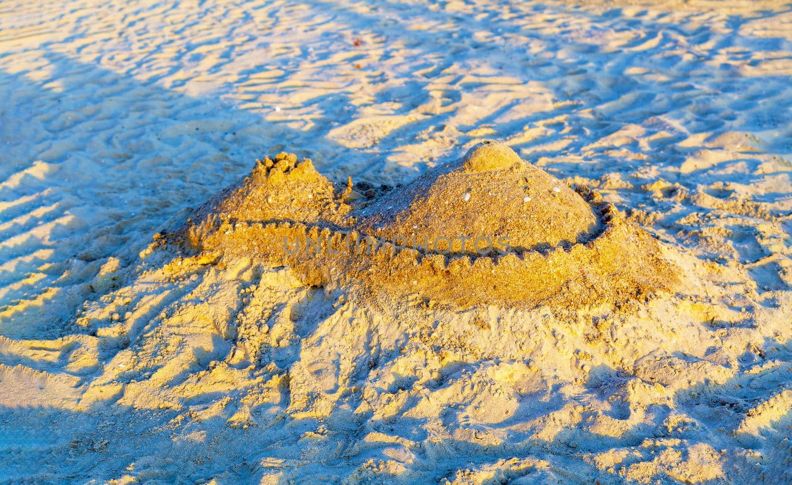 Beautiful sand castle illuminated by the morning sun on the beach of the tropical sea. The concept of a family vacation at sea.