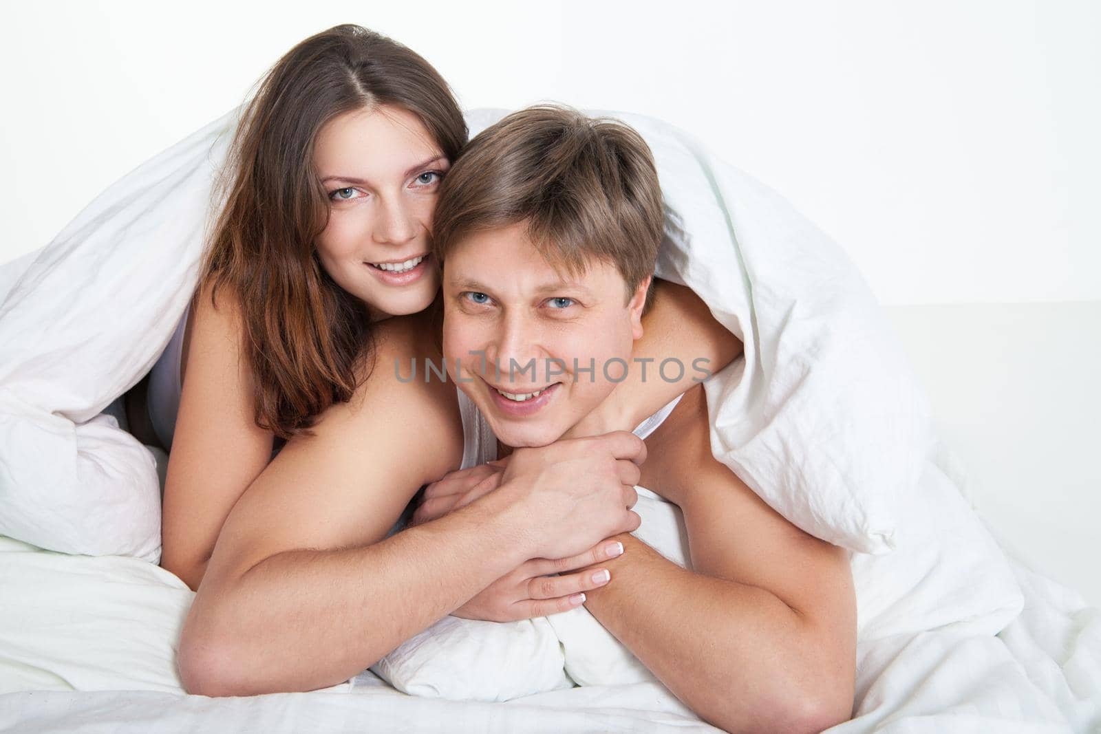 Beautiful young couple relaxing in bed at home by Julenochek