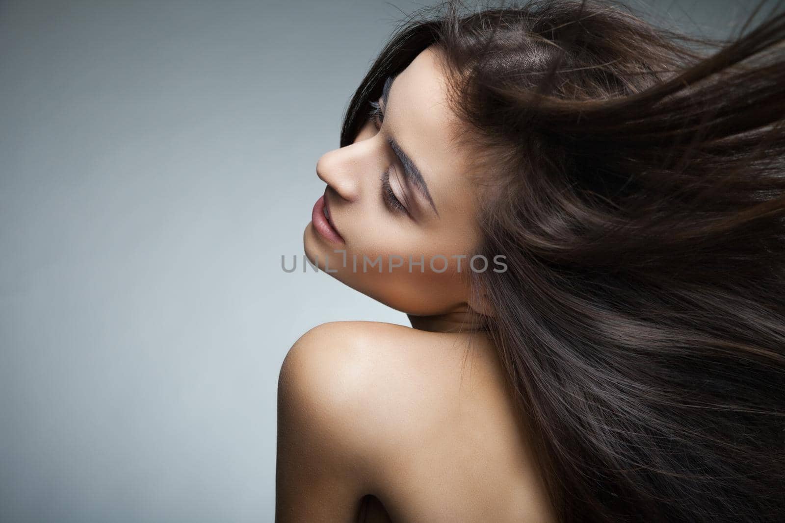 Portrait of attractive caucasian smiling woman with long hair on grey background.Looking at camera