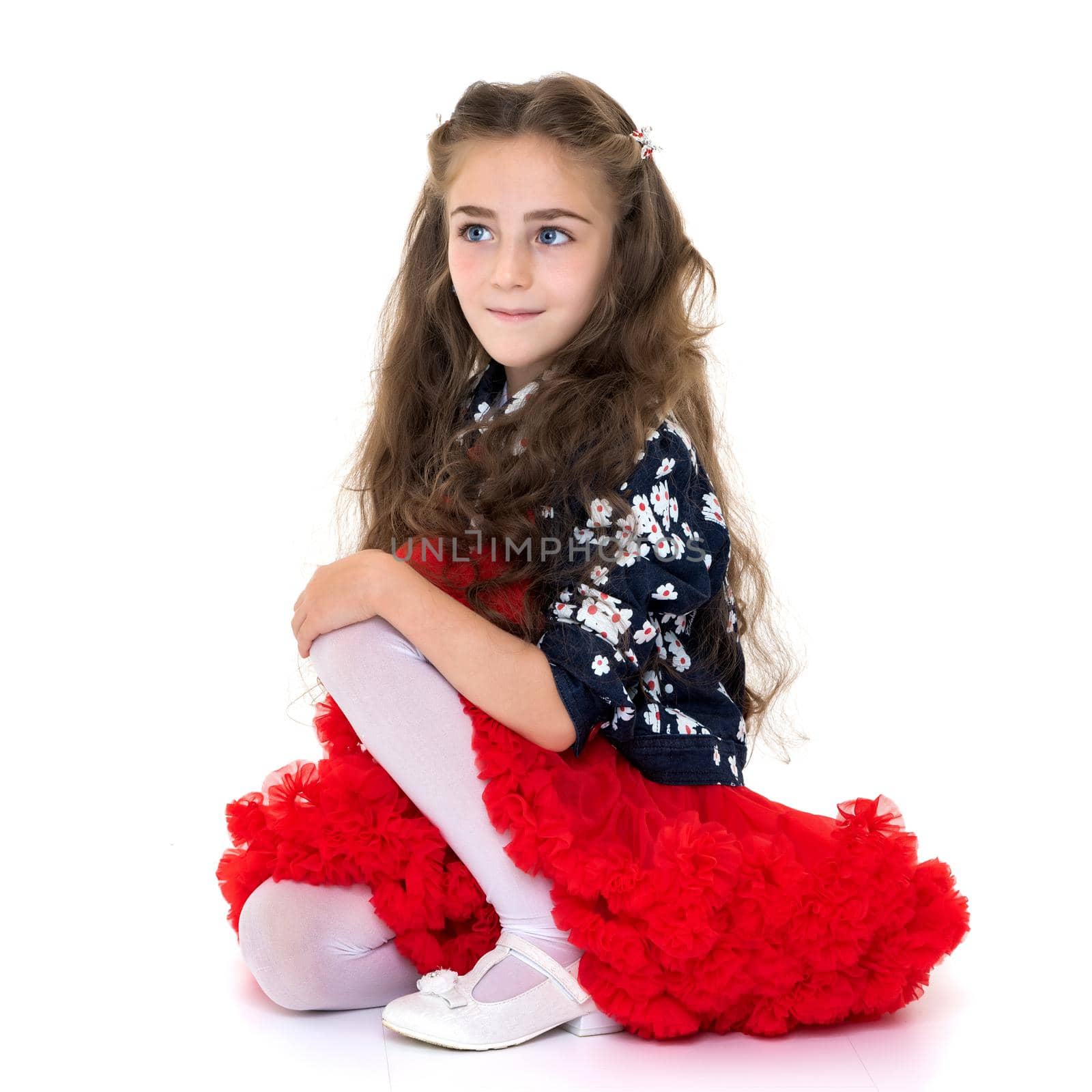 Little girl is sitting on the floor. The concept of a happy childhood. Isolated on white background.