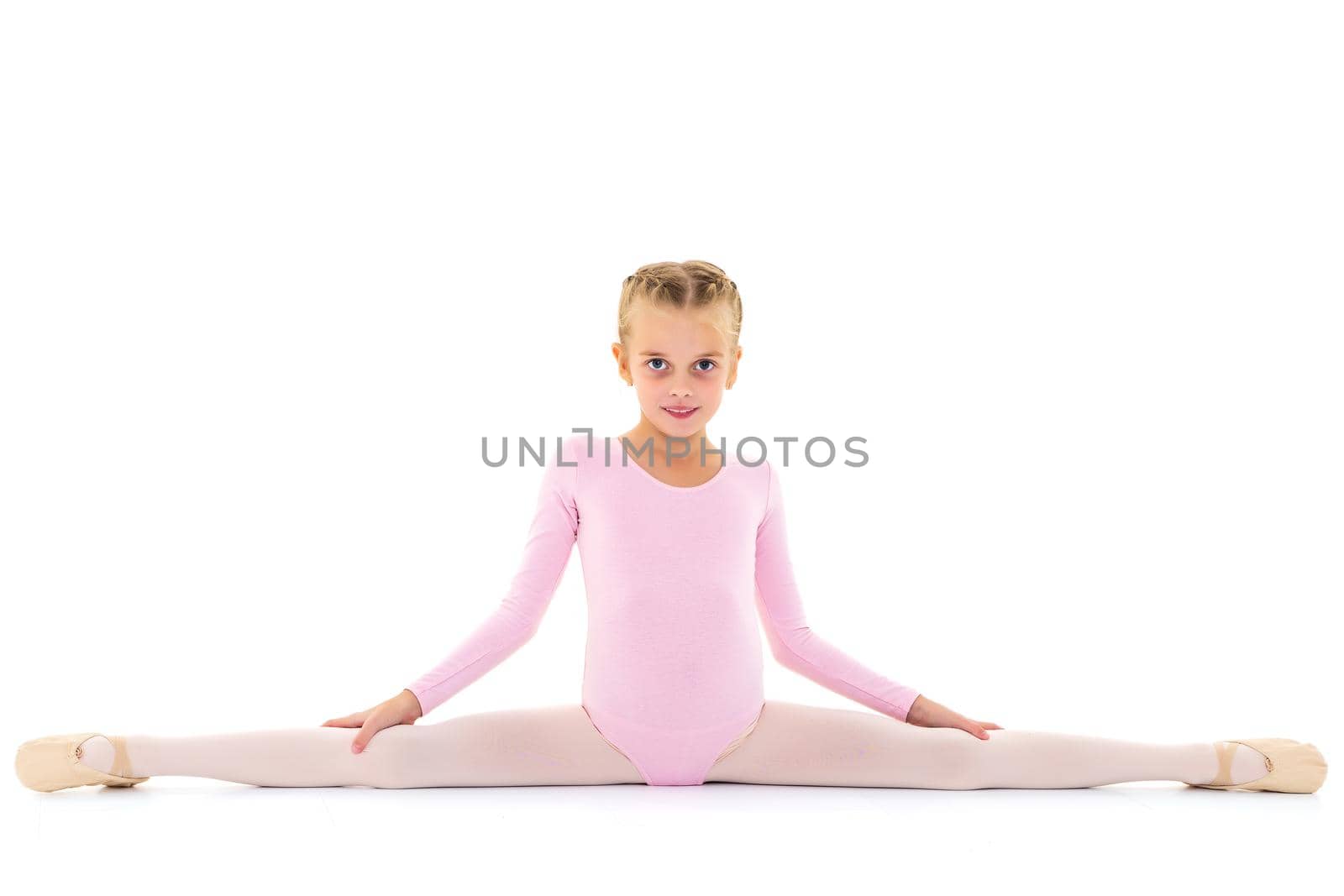 A little girl performs a gymnastic twine. The concept of fitness and sports. Isolated on white background.