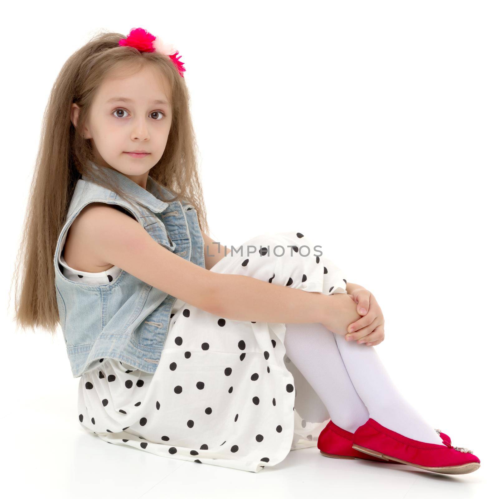 Cute girl posing on the floor in the studio. Hugs his knees. Isolated on white background. The concept of beauty and fashion