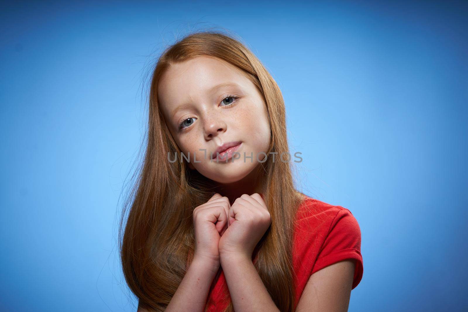 cheerful cute red-haired girl childhood blue background. High quality photo