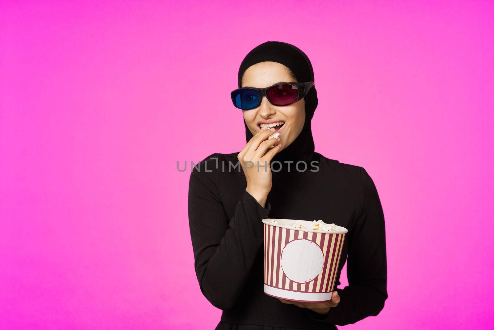 Muslim woman attractive look popcorn glasses movie watching studio lifestyle. High quality photo