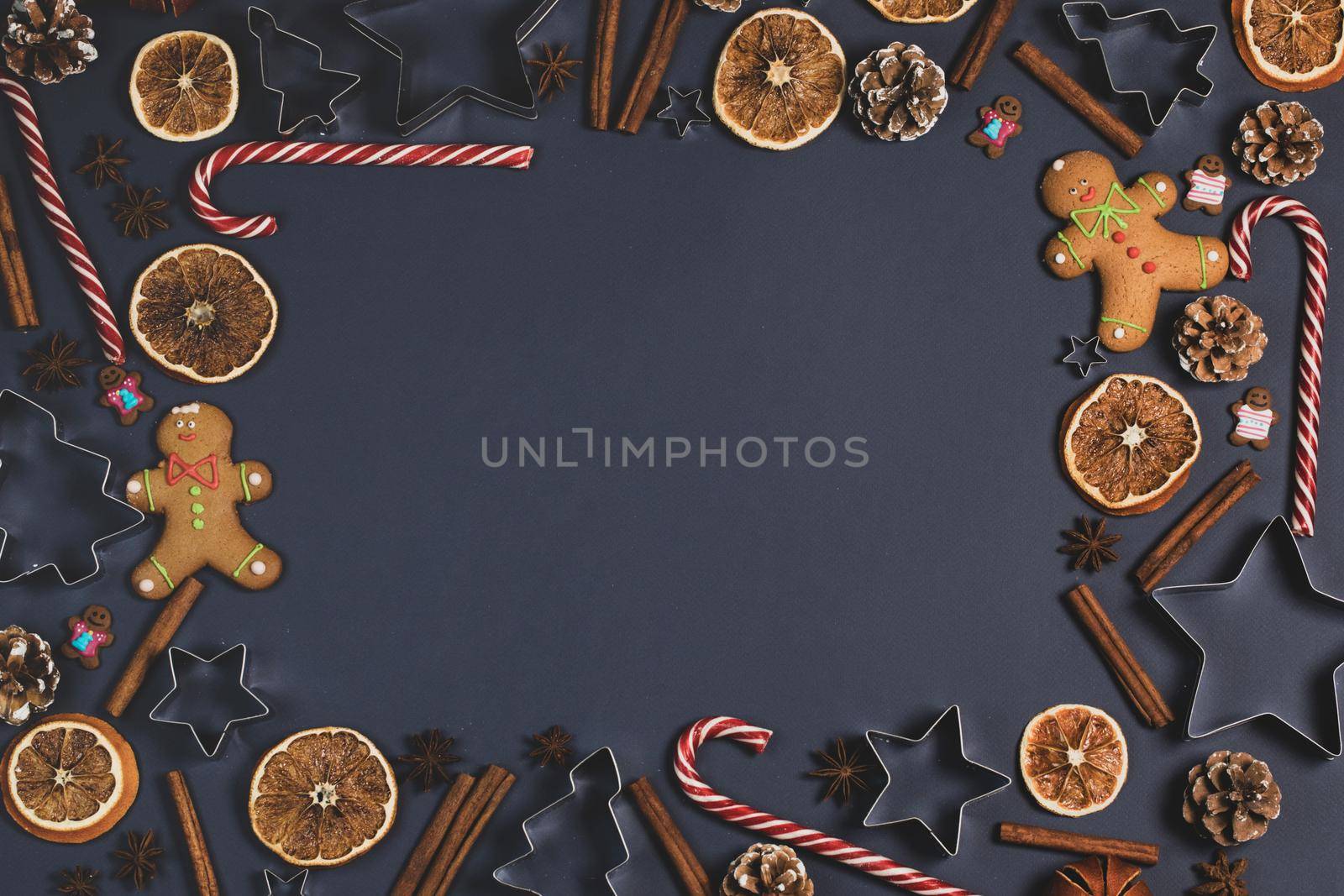 Christmas food border frame. Gingerbread cookies, spices and decorations on dark background.