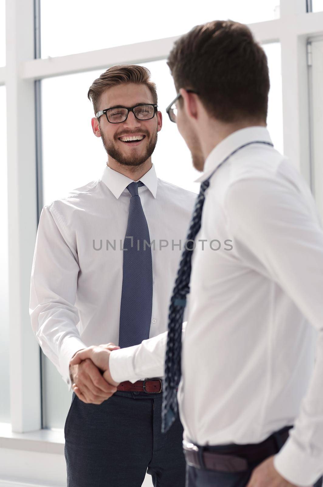 close up.handshake of business partners standing outside an office window. by asdf