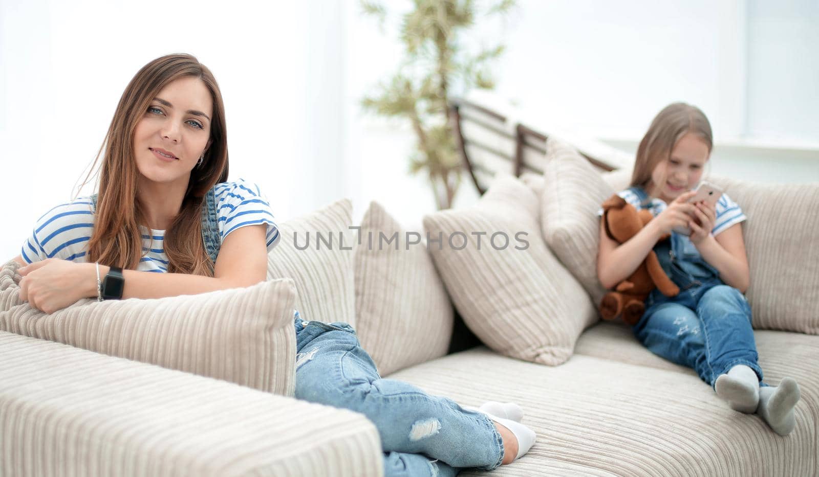 young housewife and her little daughter sitting on the couch.photo with copy space