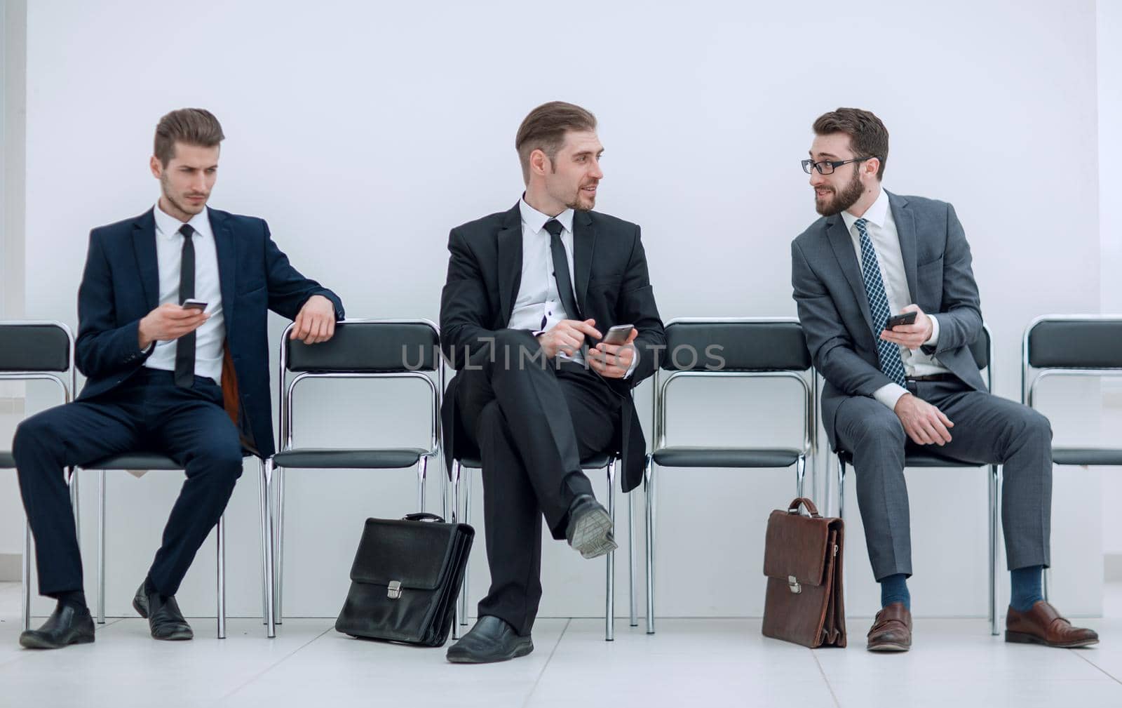 employees with smartphones sitting in the office hallway.photo with copy space
