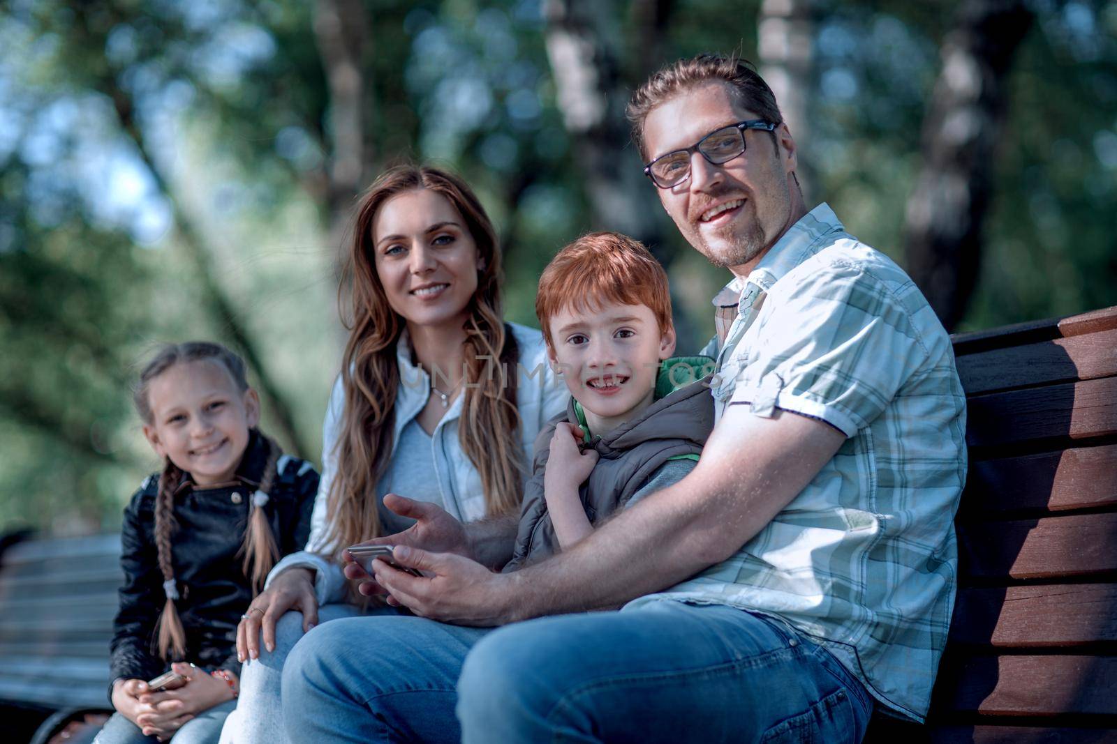 happy family sitting on bench in summer Park.the concept of family entertainment
