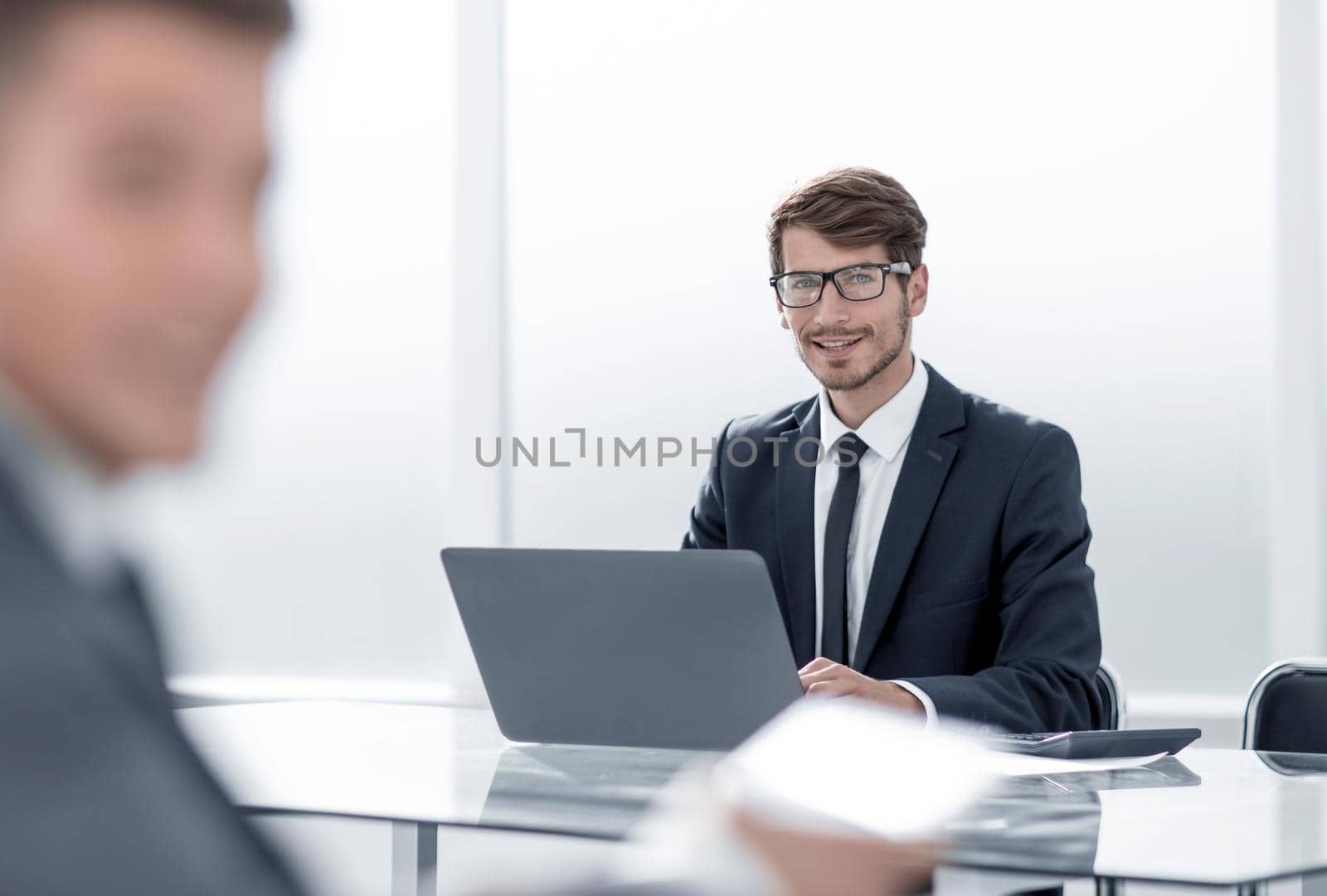 young businessman looking at computer, his colleague using tablet