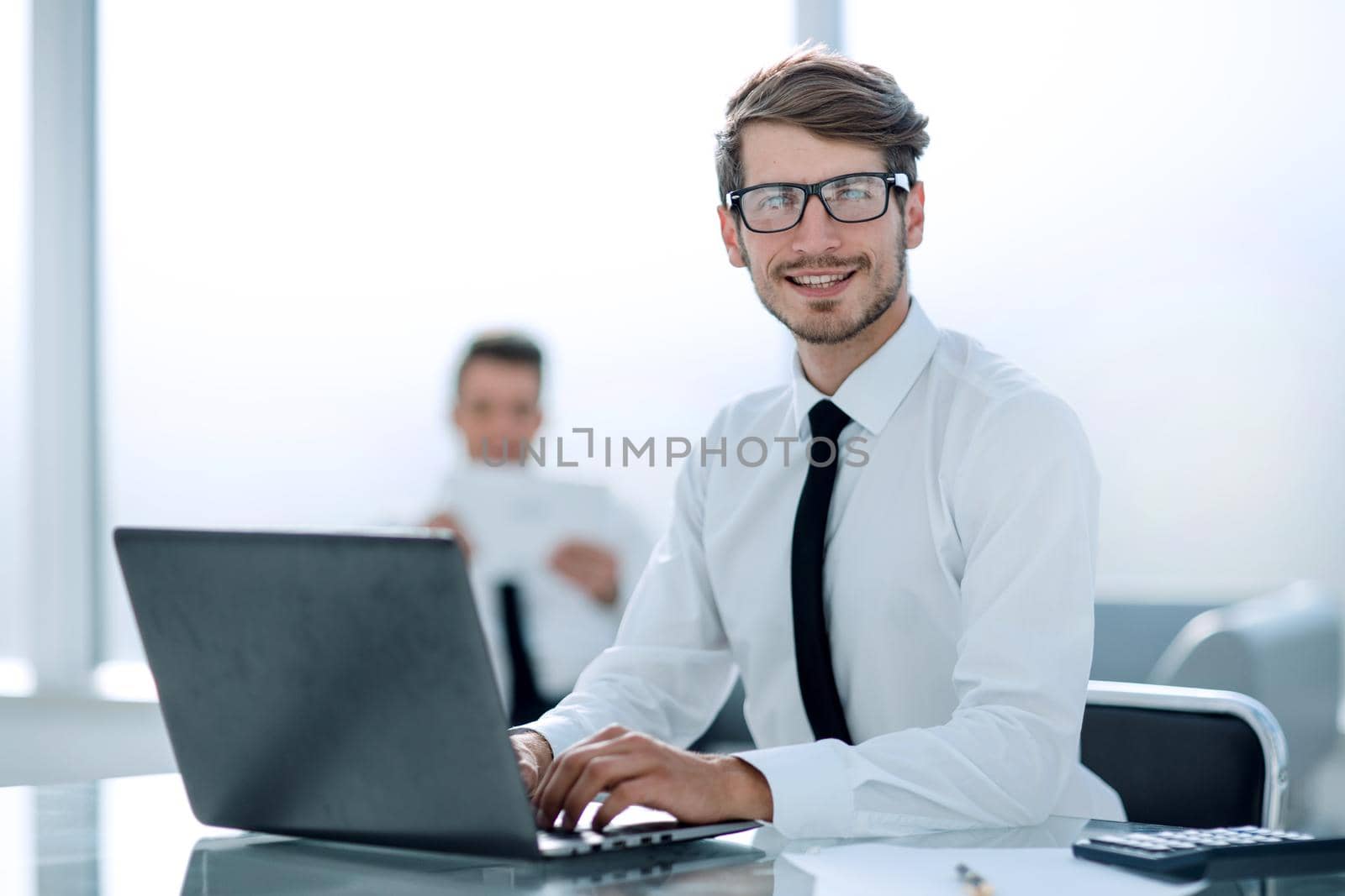 Successful young businessman typing on laptop at workplace by asdf