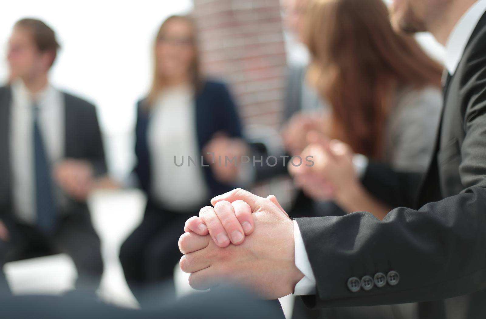Young people are sitting in circle, holding hands and smiling