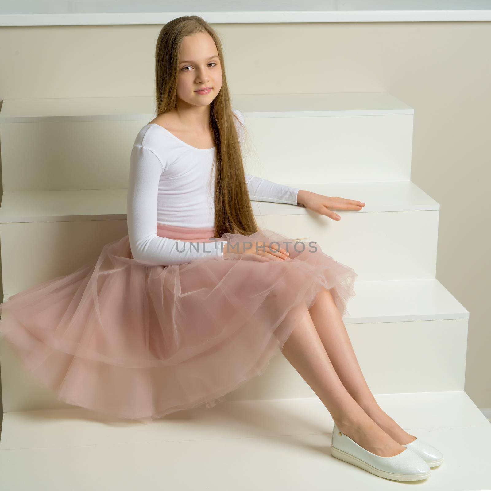 Beautiful little girl is sitting on the white staircase. by kolesnikov_studio