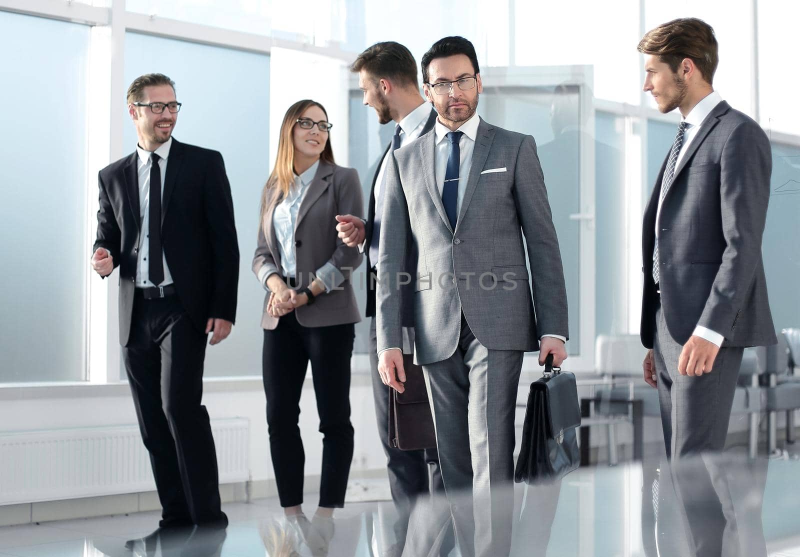 business people group standing together as team by window in modern bright office interior