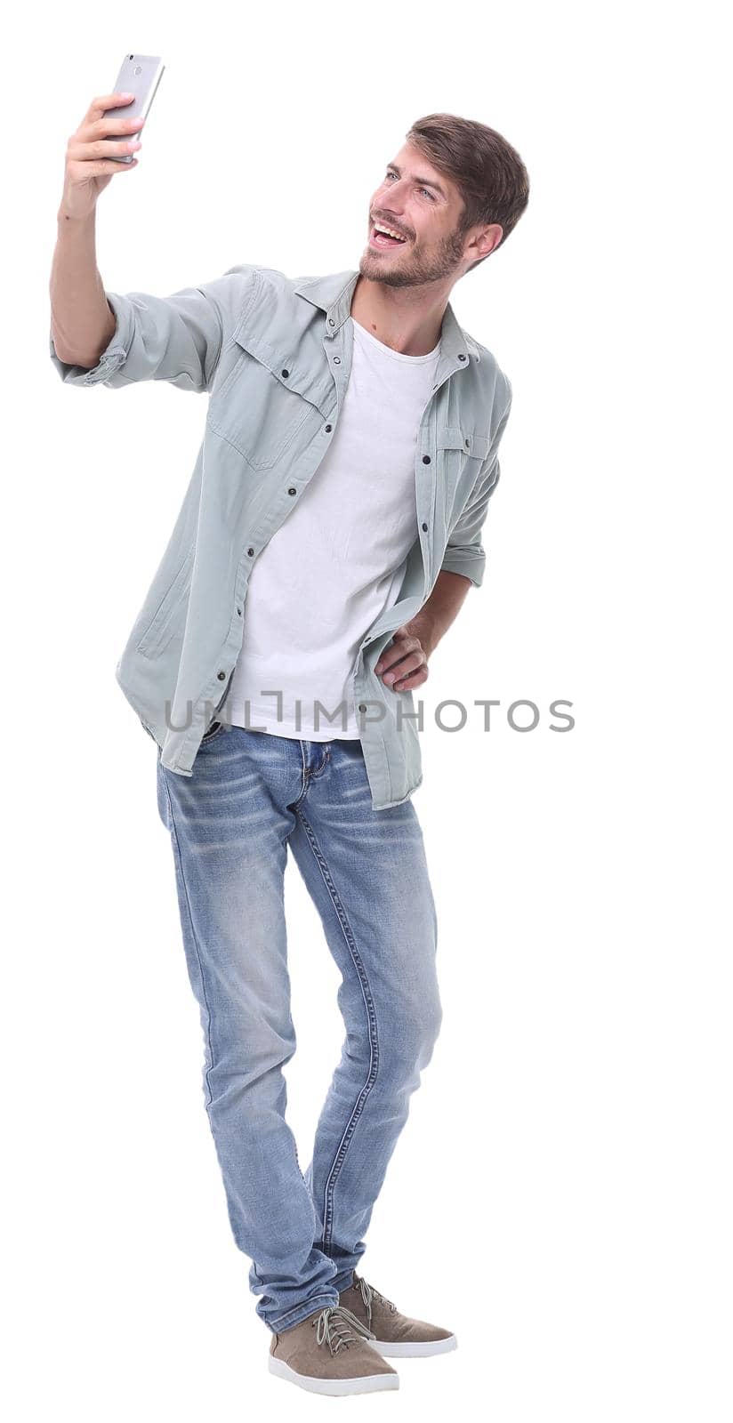 in full growth.smiling young man taking selfie.isolated on white background.