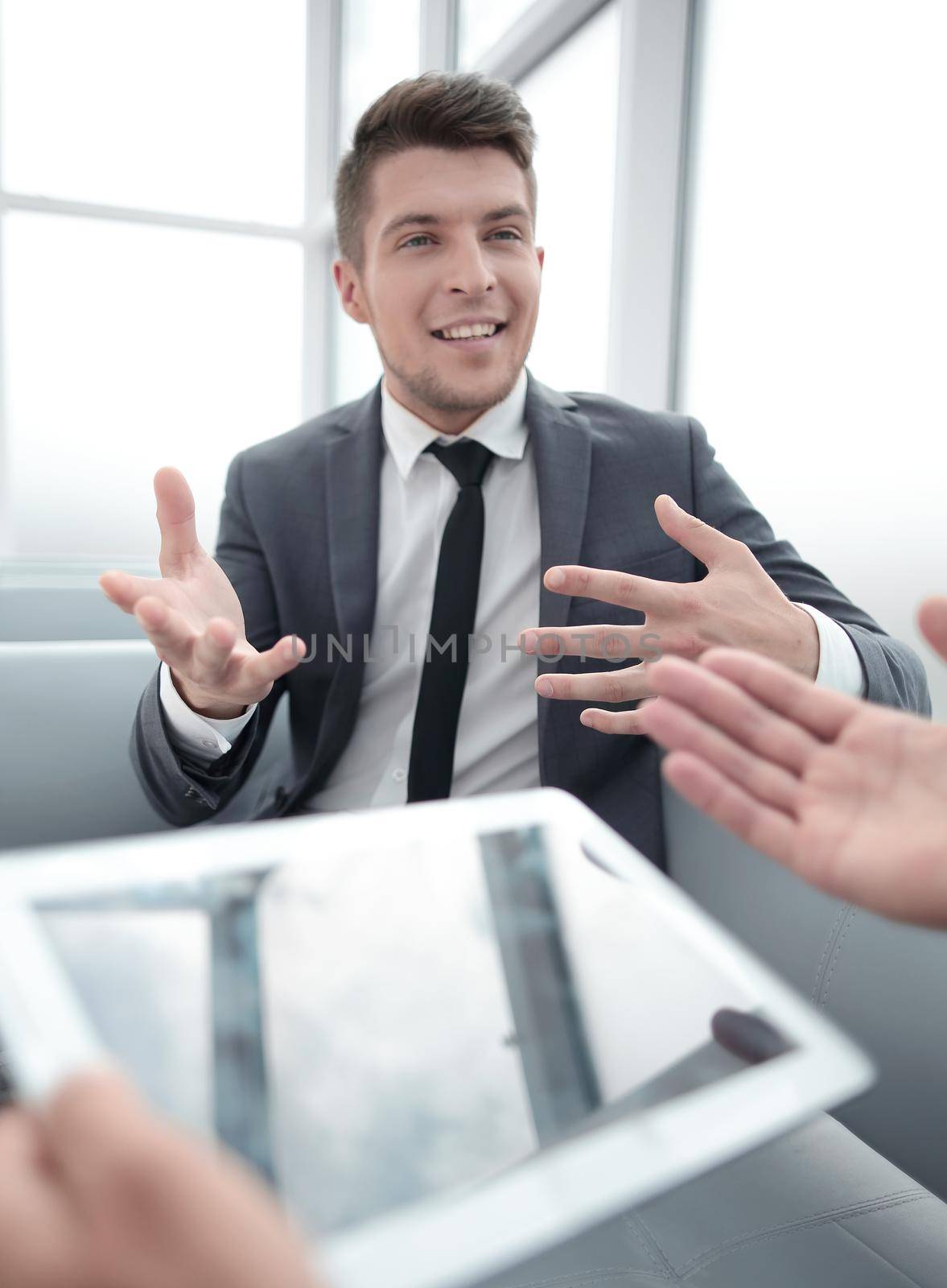 man having tablet in hands,having conference, conversation with her partners, one man on blurred background