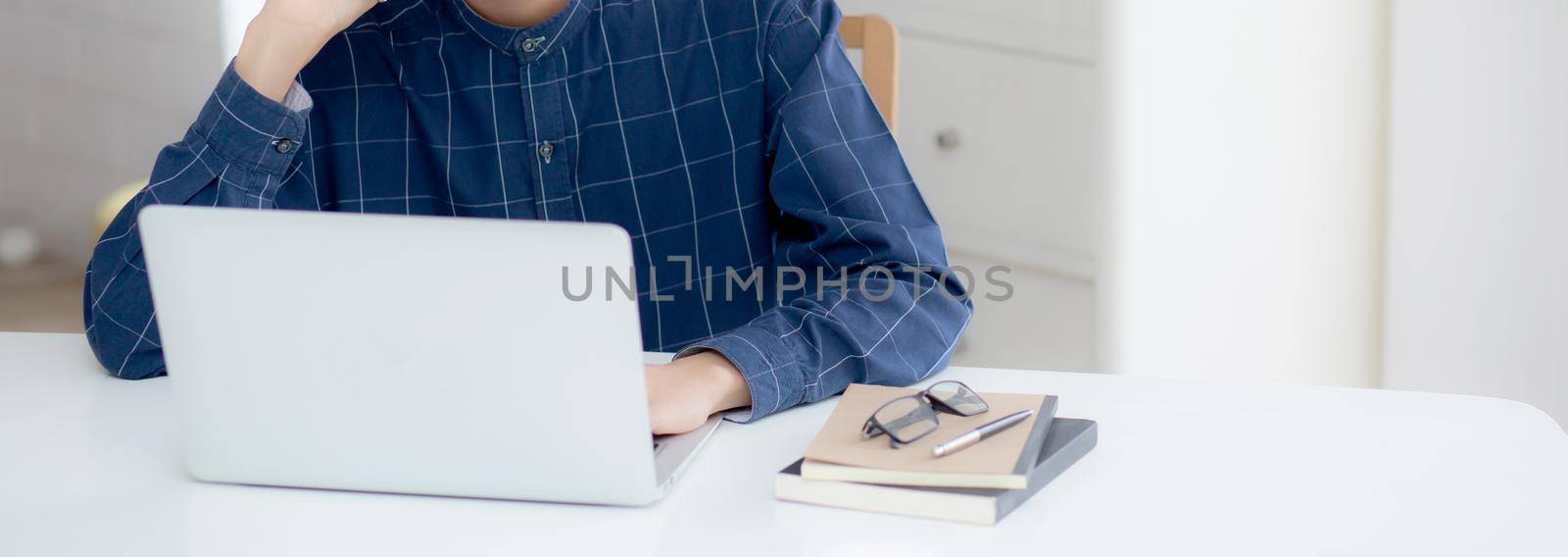 Hand of young man working on laptop computer on table at home office, male typing keyboard notebook on desk, businessman surfing to internet online or check mail, business and communication concept. by nnudoo