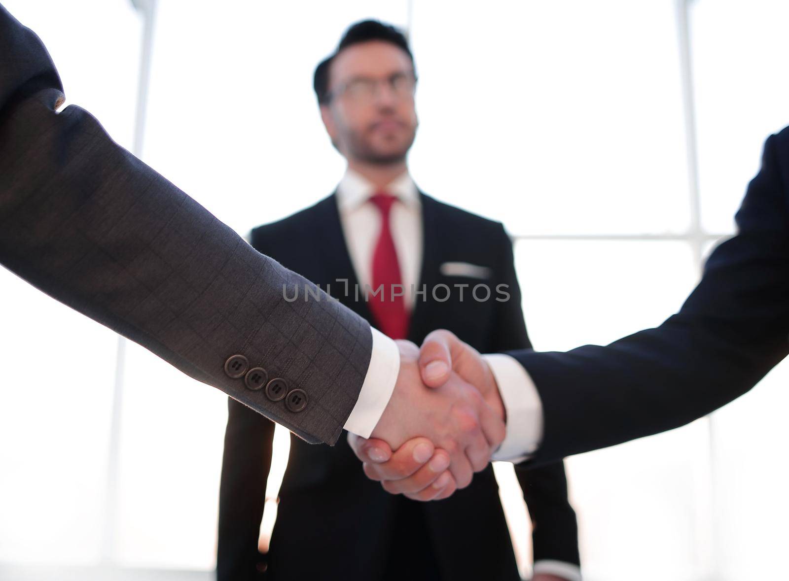 in the foreground is the handshake of business people.business background