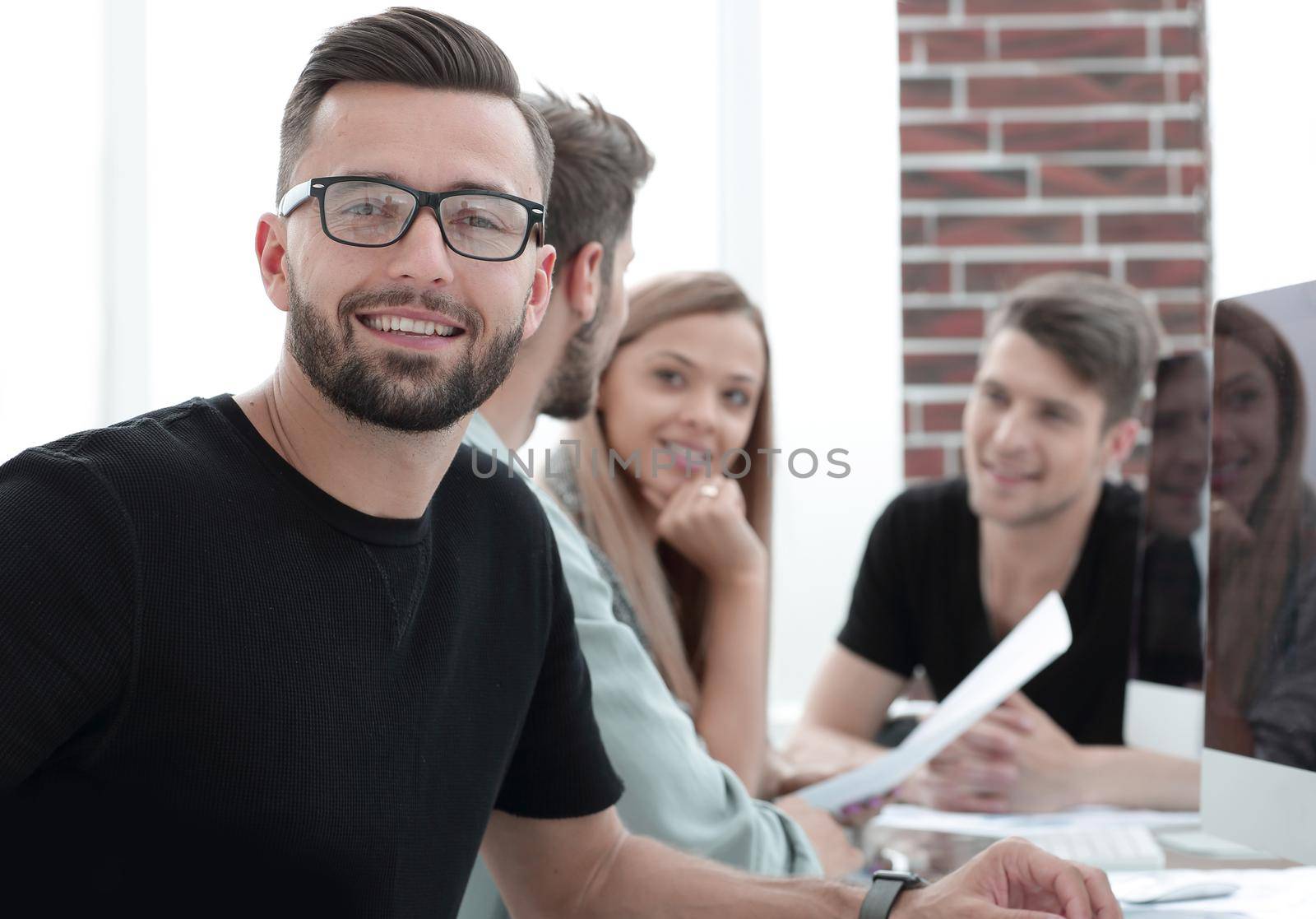 Success conception. Portrait of gorgeous young businesman in glasses sitting at her workplace in the office