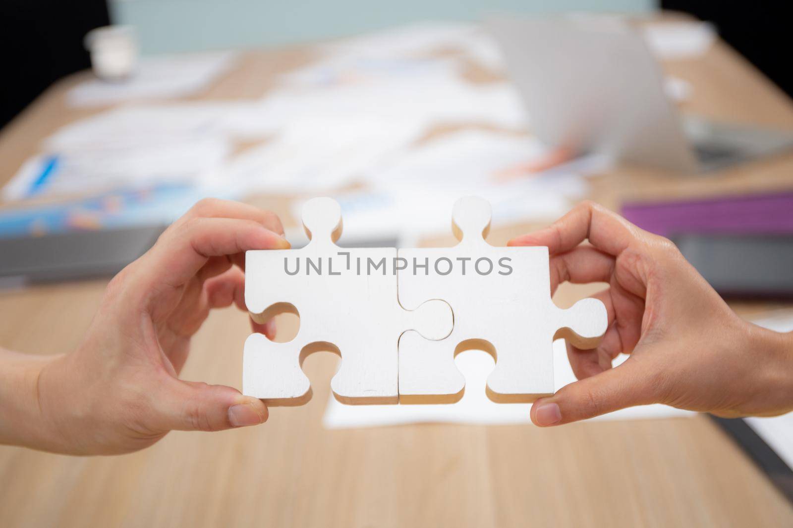 Hands of team young business and partner holding piece jigsaw for assembly is metaphor, teamwork symbol, bonding and harmony in team, friendship and marketing, business and communication concepts.