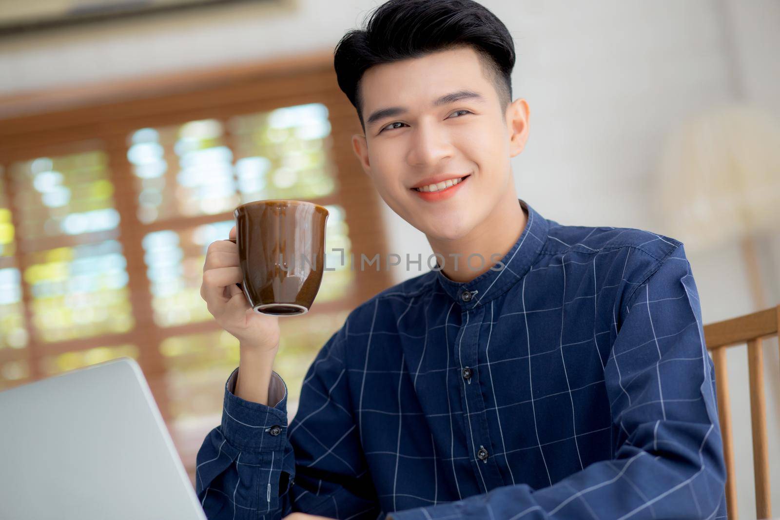 Young business man working from home with laptop computer on desk, freelance male sitting stay home using notebook for communication and relax on table, entrepreneur in startup business, new normal. by nnudoo