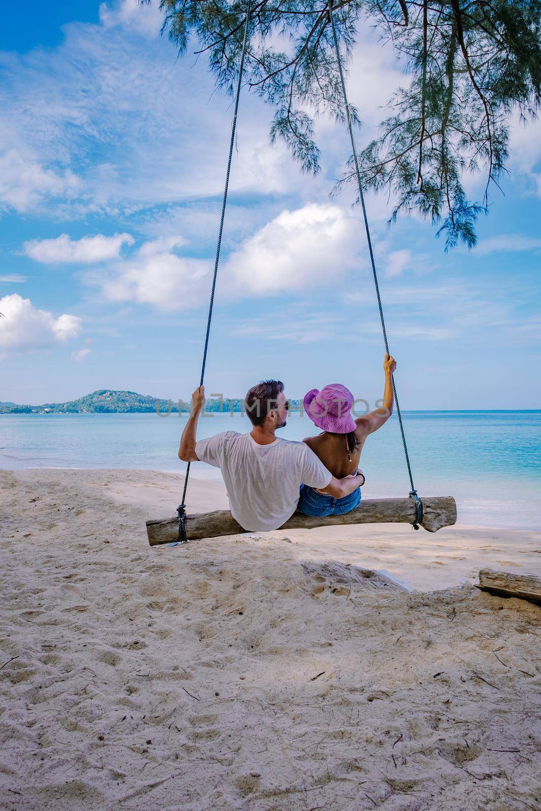 Bang Tao Beach Phuket Thailand, beach with palm trees and a Couple man and women in the swing on the beach. Summer, Travel, Vacation, and Holiday concept - Swing hangs from coconut palm tree
